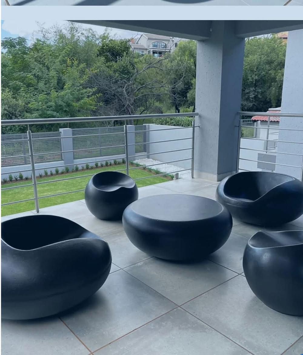 Black hand-cast concrete ball chairs and table on a covered patio